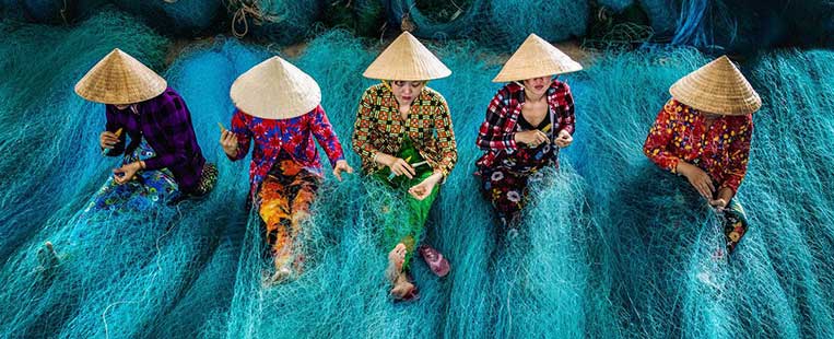 Las mujeres vietnamitas llevan sombreros cónicos en el trabajo