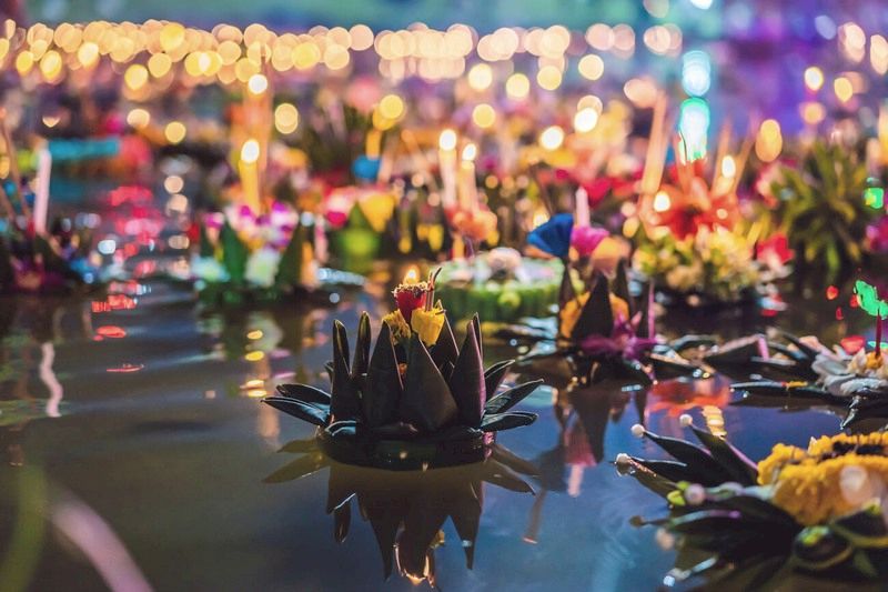 El luminoso Krathong decorado con flores y velas flotando en el agua.