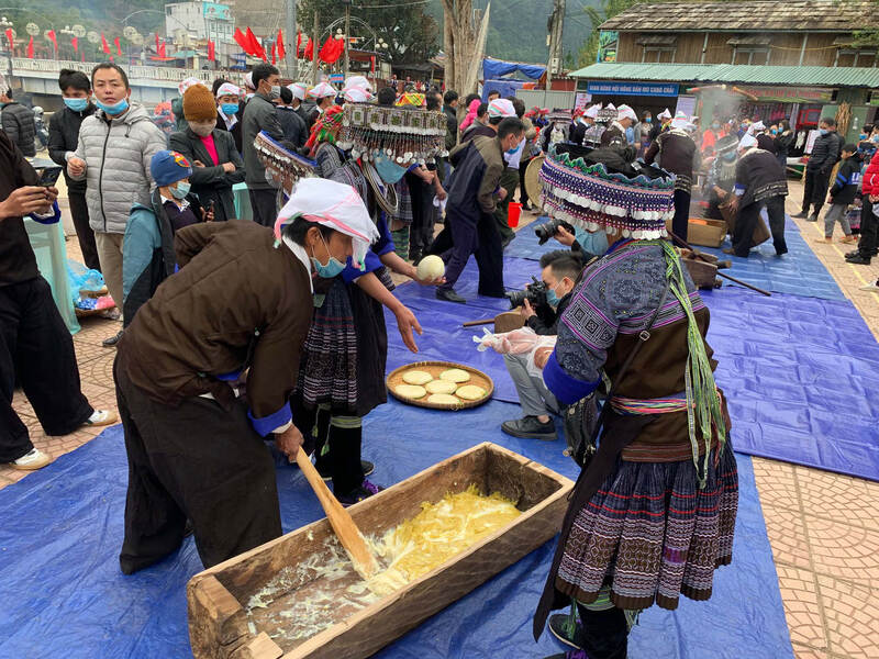 Hmong women and men pounding and shaping rice cakes