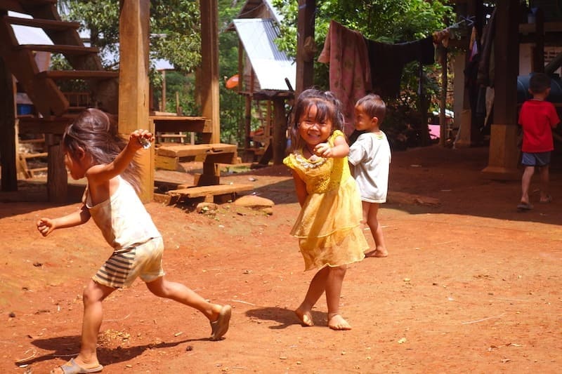 Ethnic children play in the courtyard of stilt houses