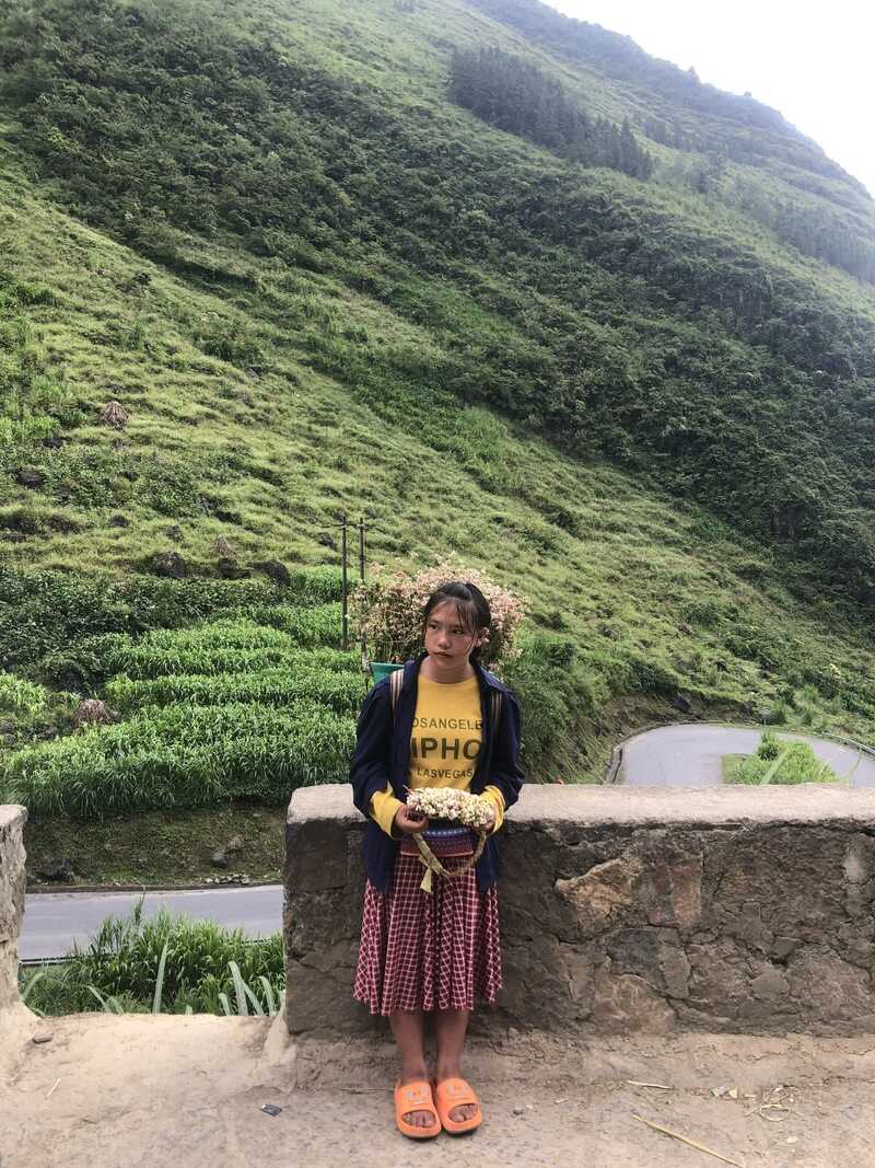At Ma Pi Leng Pass, young ethnic children often sell bright triangle flowers and pose for photos with tourists.