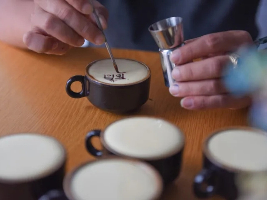 Travelers learning to brew traditional Vietnamese egg coffee using a Phin filter during a workshop in Hanoi.