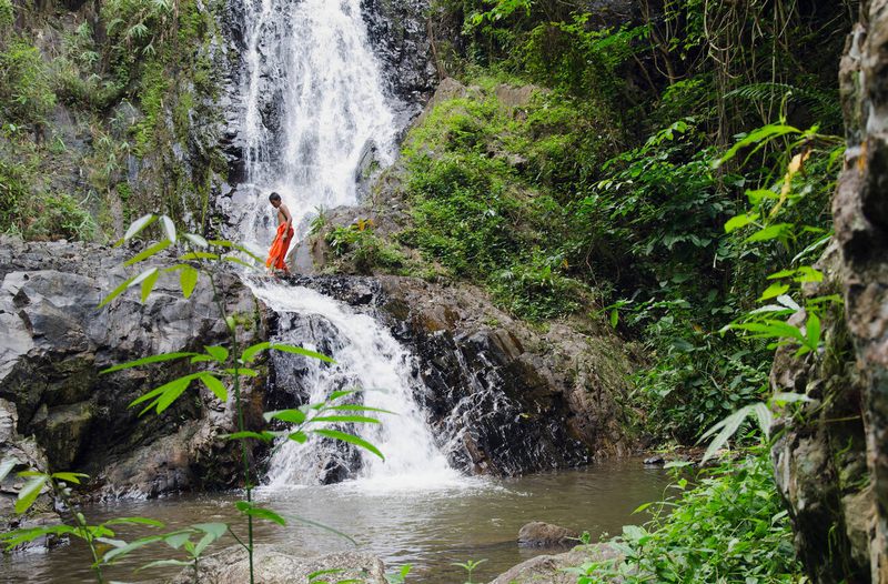 Monk crossing a waterfall at Khao Phanom Bencha National Park.