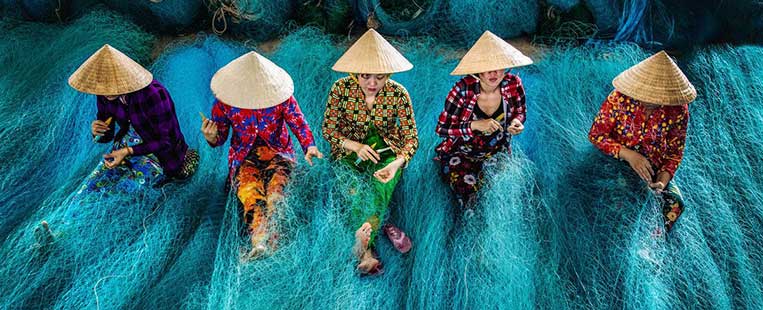 Vietnamese women wear conical hats at work