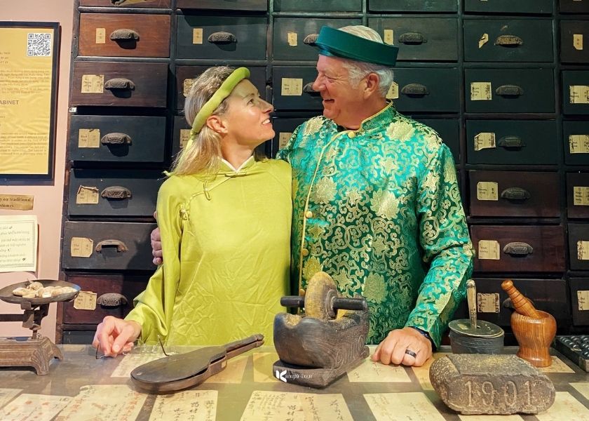 Kampá Tours travelers are dressed in traditional Vietnamese attire, posing for a photo celebrating their 25th wedding anniversary.