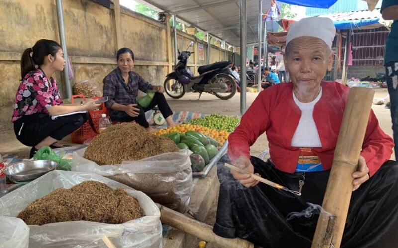 A Hmong woman smoking tobacco at the market.