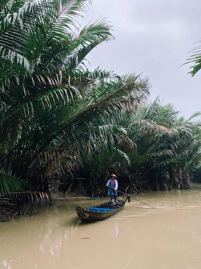 A skilled boatman navigating the calm waters of the Mekong Delta