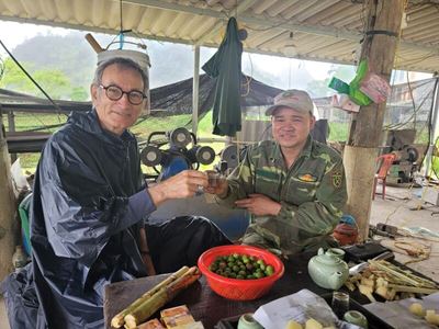 A moment of camaraderie: Mr. Patrick shares a toast to simple pleasures with a local amidst the serene backdrop.