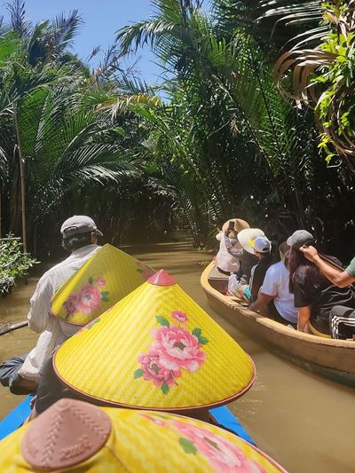 Con el sombrero cónico, navegando por el canal en el bosque de manglares del Delta del Mekong.