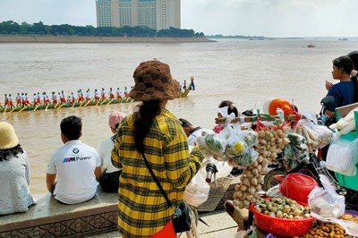 La gente observa regatas en la orilla del río.